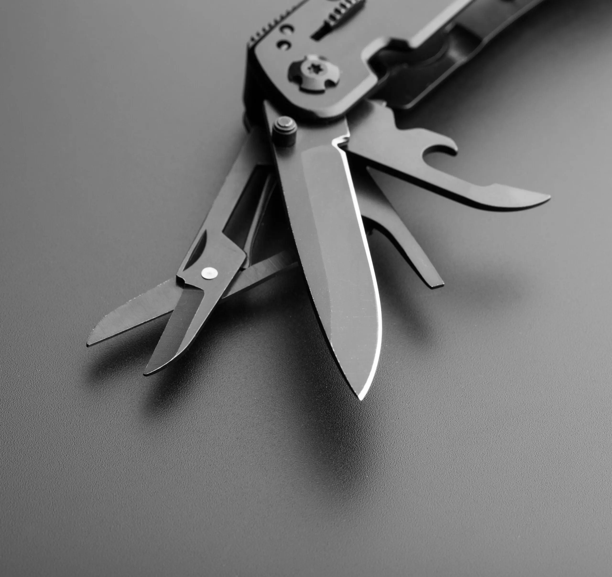 Fotografía en blanco y negro de una navaja suiza multifuncional abierta mostrando sus diversas herramientas. Simboliza la propuesta de valor como una 'navaja suiza' tecnológica, actuando como una extensión estratégica del negocio para solucionar problemas con el equipo exacto de expertos.