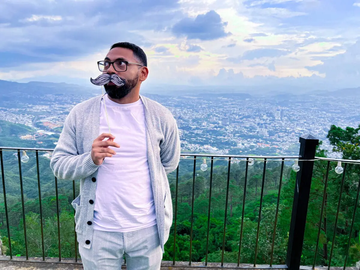 Colaborador de Andes Development posando con un bigote de utilería en el mirador durante la convivencia del 12º aniversario. Una muestra de las dinámicas de integración y el excelente clima organizacional de la empresa.