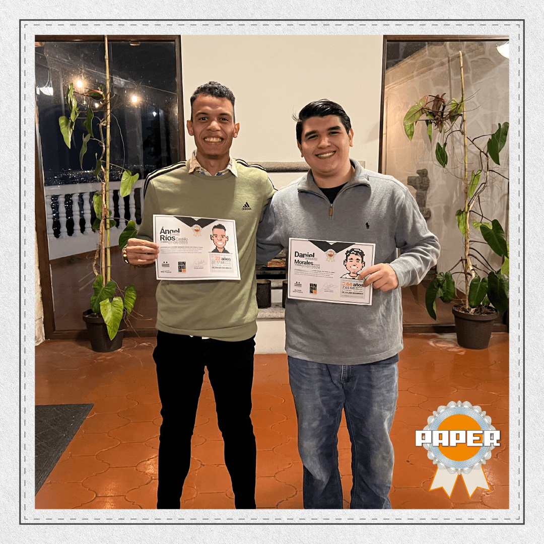 Ángel Ríos y Daniel Morales posando sonrientes con sus diplomas del Premio Paper durante la celebración del 12º aniversario de Andes Development. Este premio reconoce su talento, crecimiento y dedicación durante sus primeros dos años en la agencia.