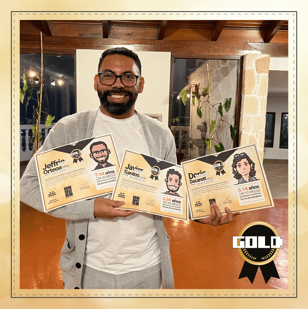Colaborador de Andes Development posando orgullosamente con tres diplomas del Premio Gold, que reconocen a los miembros del equipo (Jeffrie Ortega, Javier Santos y Doris Dacarett) con más de 5 años de trayectoria y fidelidad en la agencia durante el evento del 12º aniversario.